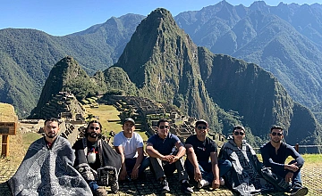 Foto grupal de viajeros en Machu Picchu con vista panorámica de la ciudadela y montañas
